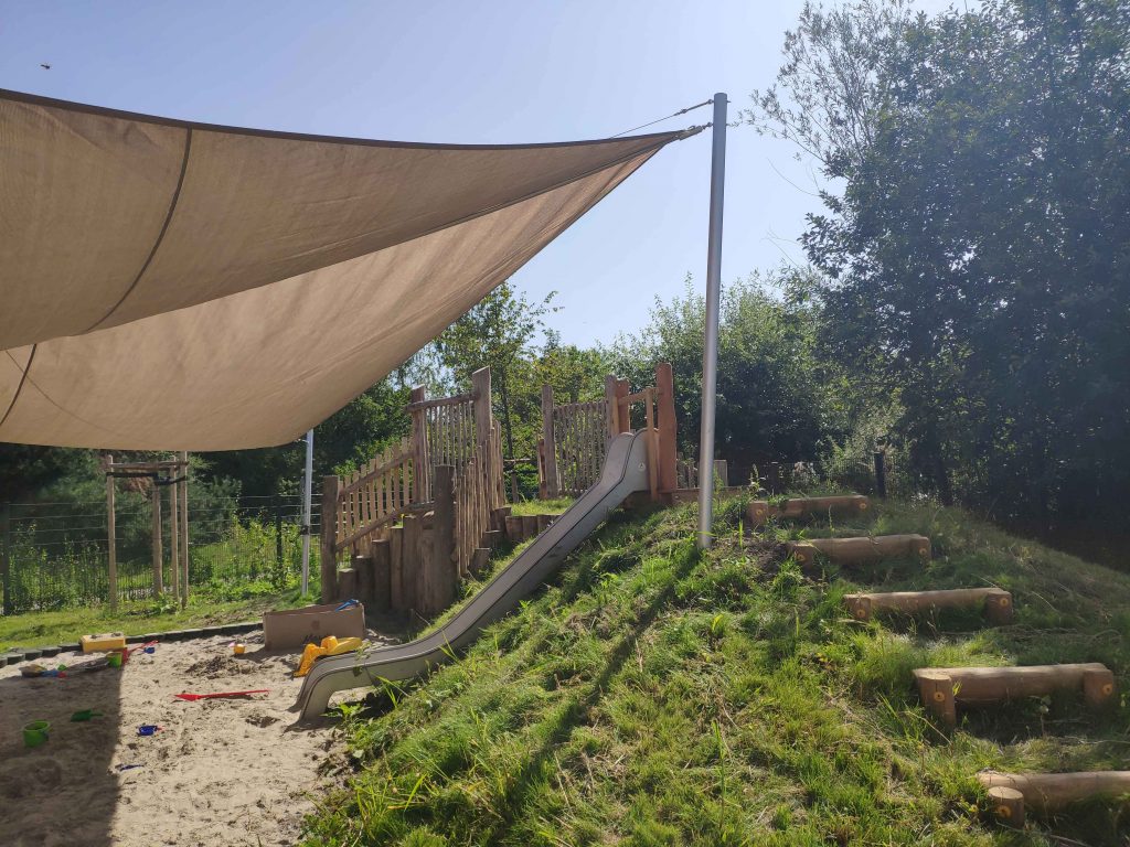 Spielplatz, Spielhügel, Sonnensegel, Rutsche, Trittstufen, Rasen, Sand, Weide